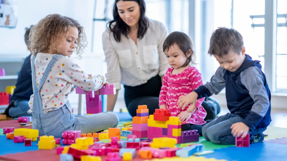 Erzieherin spielt mit Kindern in einer Kindertageseinrichtung
