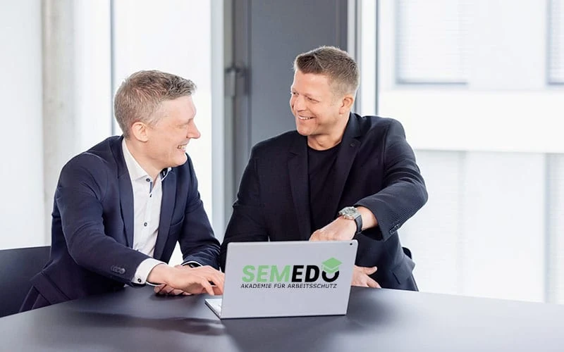 Zwei Personen im Gespräch an einem Laptop mit SEMEDO-Lernplattform