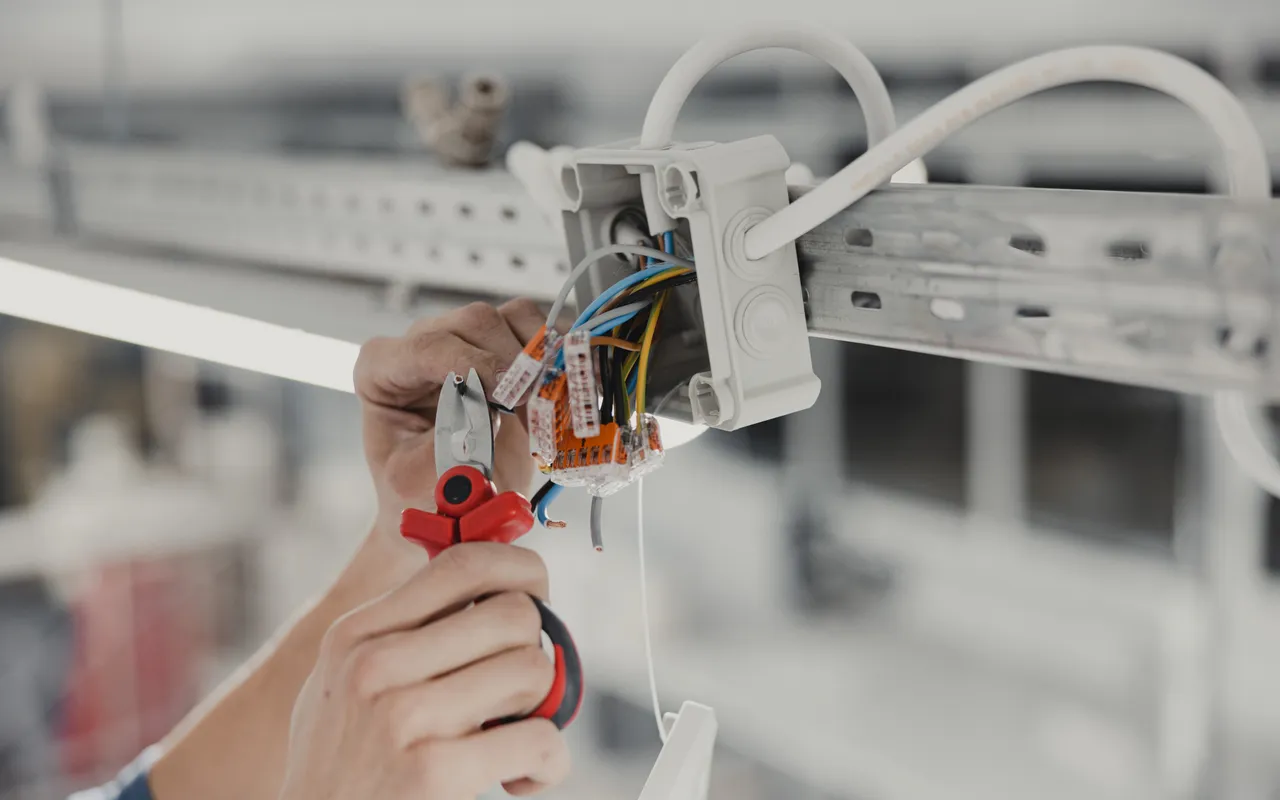 Hände verdrahten ein elektrisches Betriebsmittel
