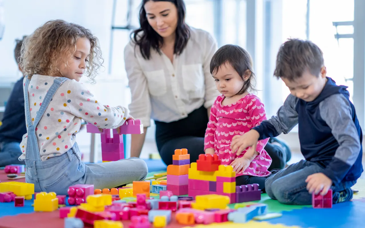 Erzieherin spielt mit Kindern in einer Kindertageseinrichtung