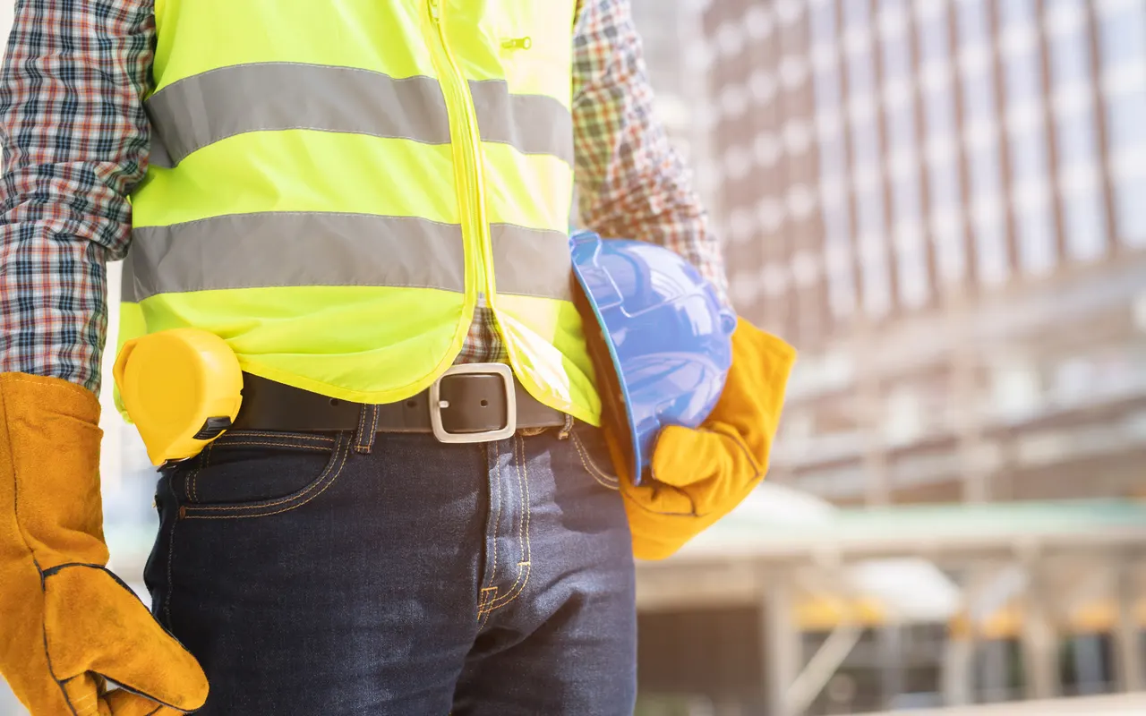 Beschäftigter mit Warnweste, Schutzhelm und Arbeitshandschuhen